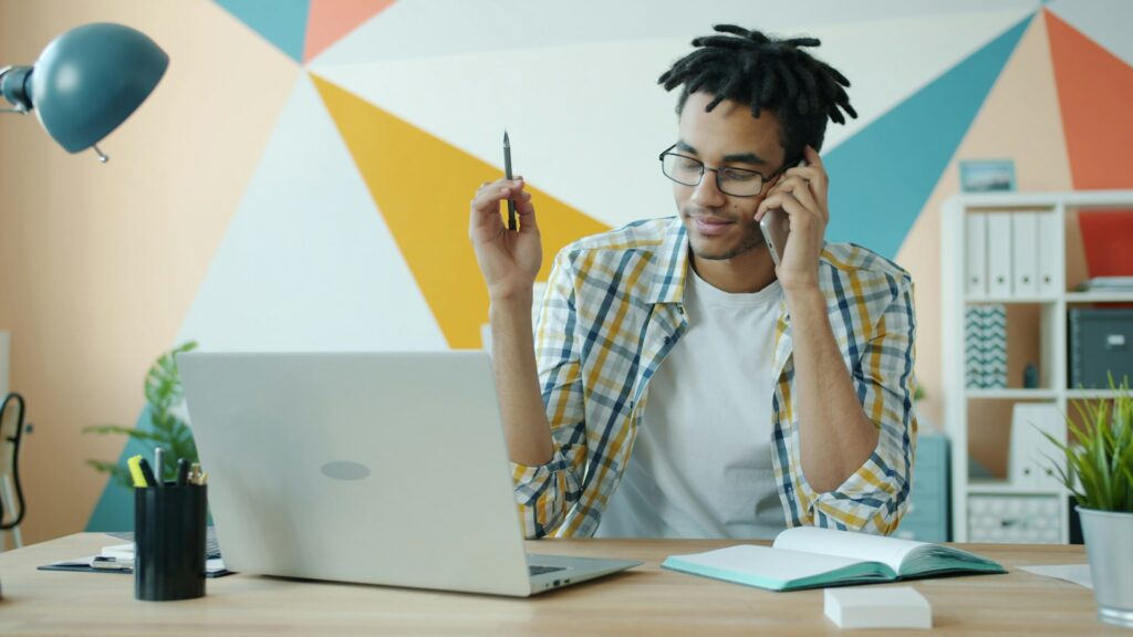 Persona trabajando en teletrabajo desde casa con portátil y cuaderno sobre el escritorio