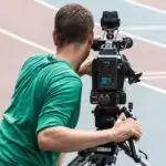 Camarógrafo grabando una competencia de atletismo con cámara profesional