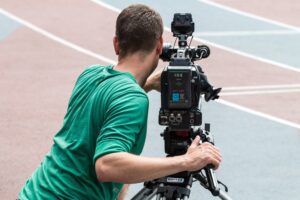 Camarógrafo grabando una competencia de atletismo con cámara profesional para el debido proceso deportivo