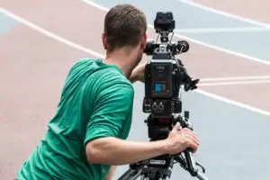 Camarógrafo grabando una competencia de atletismo con cámara profesional para el debido proceso deportivo
